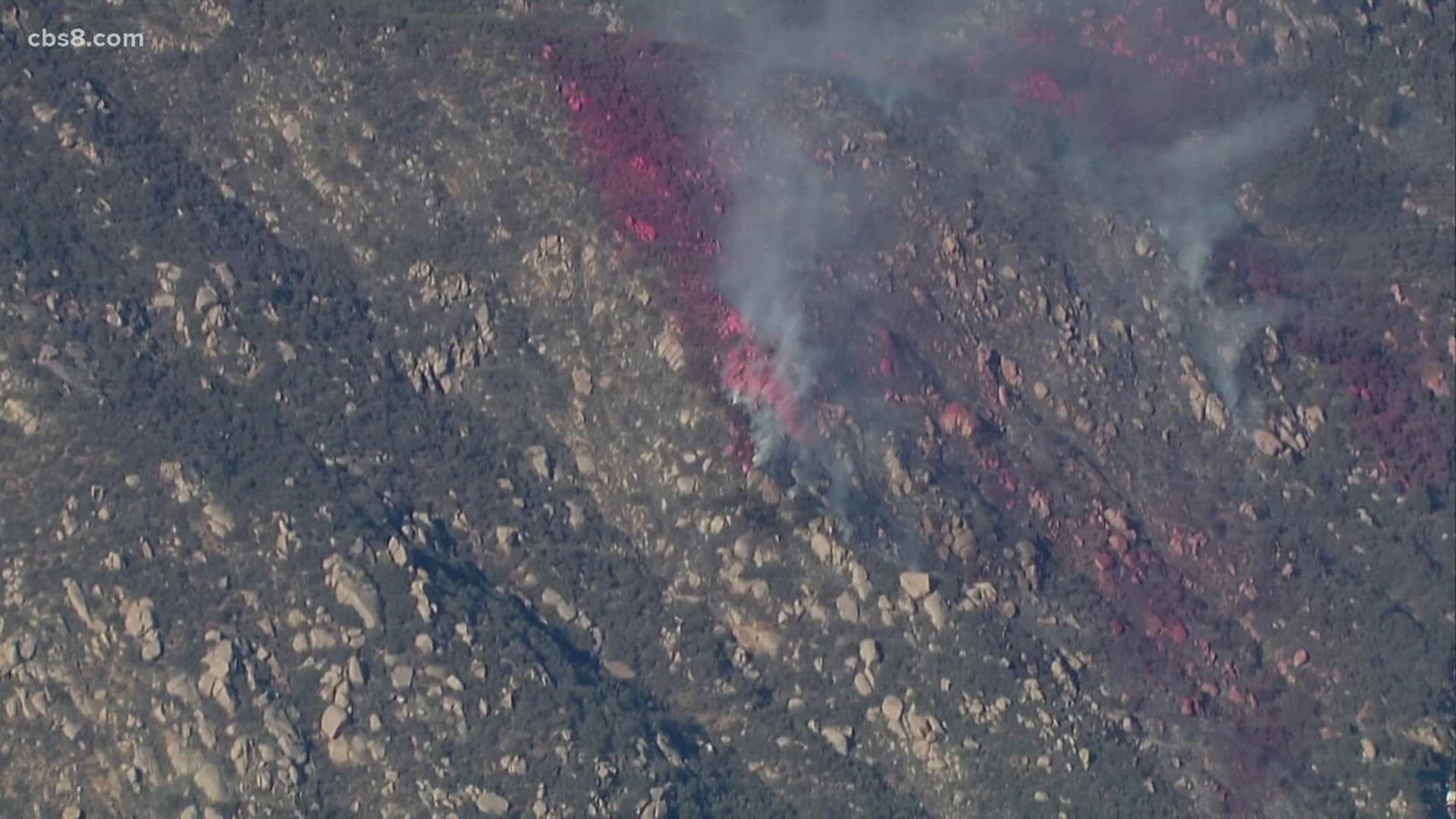 A burning car ignited a brush fire that blackened about nine open acres of a hilly rural area near El Capitan High School Monday before it was halted at 2:15 p.m.