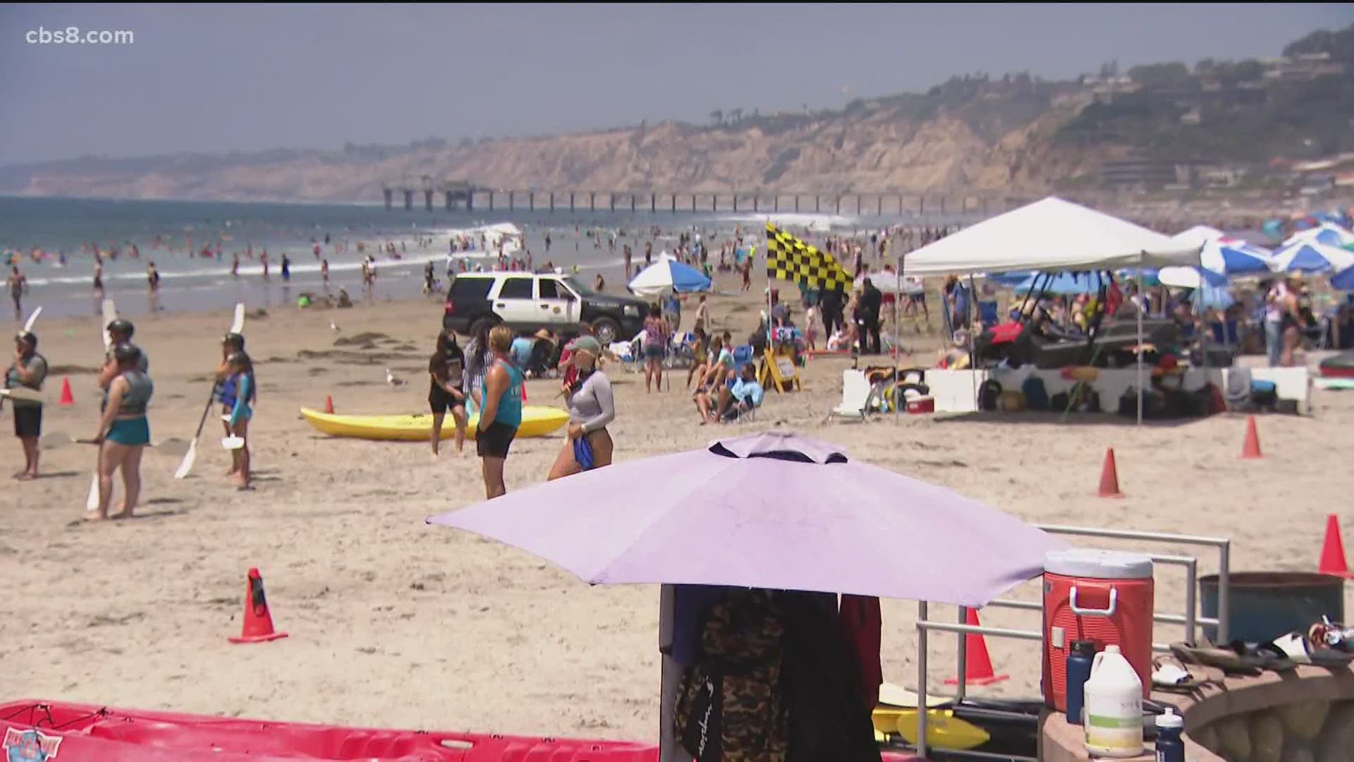 Large crowds flocked to San Diego beaches Friday at the start of the Fourth of July weekend as positive coronavirus cases surged throughout the county.